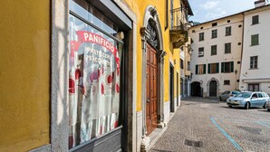 Vista de la calle con una panadería llamada "PANIFICIO PASTA SACCHETTO" a la izquierda.