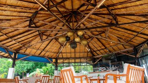 A covered outdoor seating area with wooden furniture and a thatched roof. - Ultra Winds Mountain Resort (Baungon)