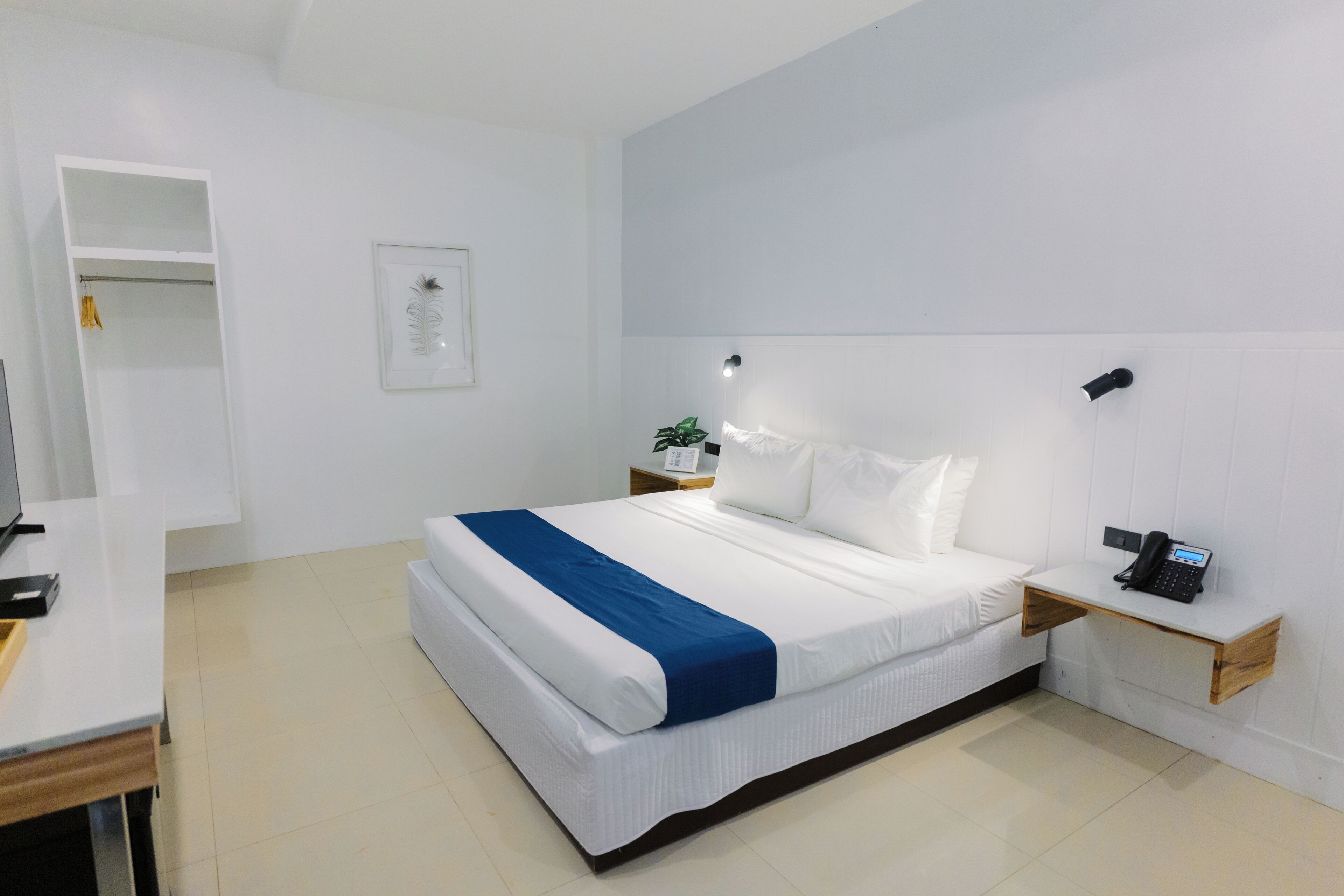 Una habitación de hotel moderna con una cama grande, mesitas de noche, un escritorio y un armario.