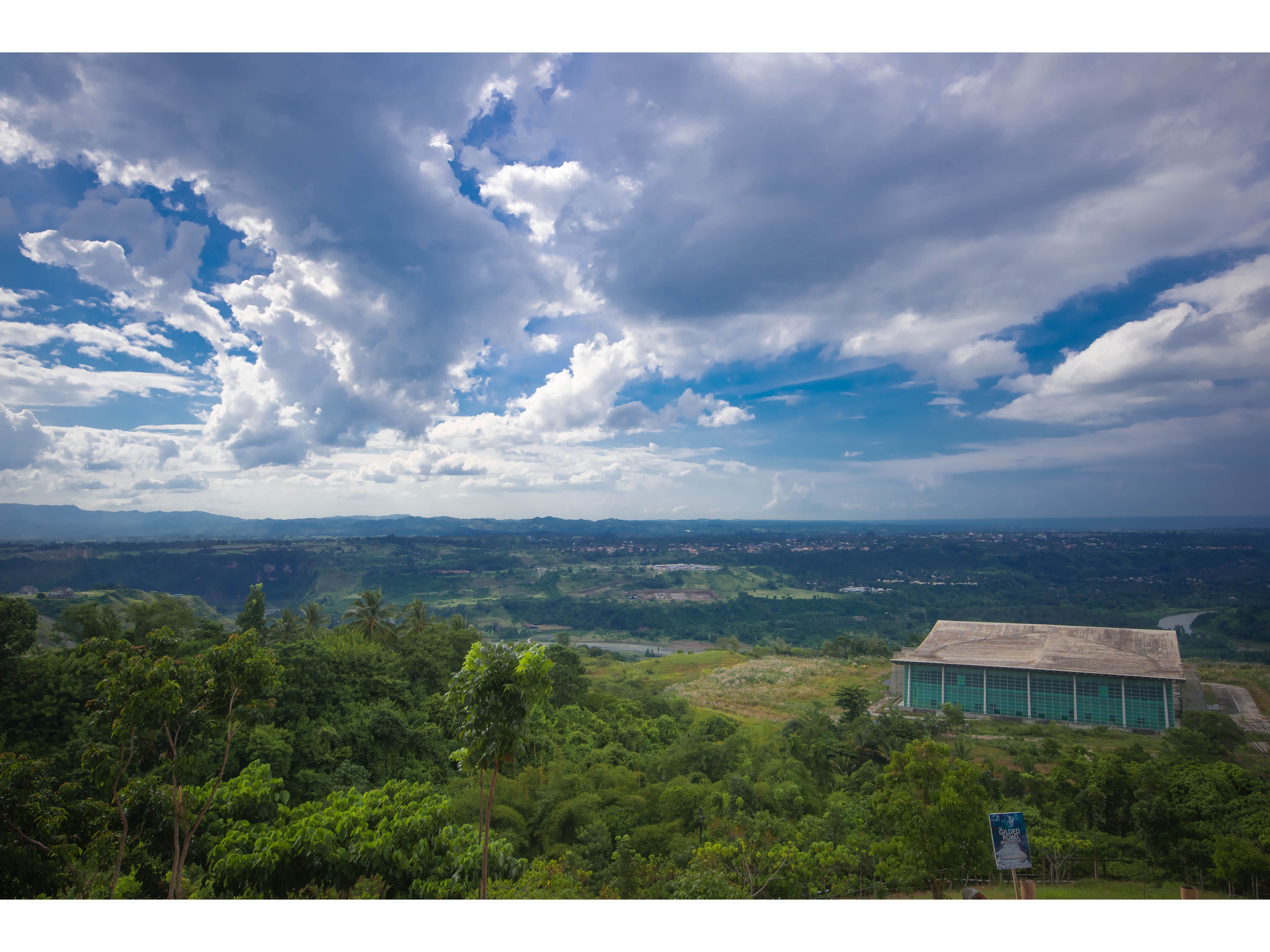 A view of a landscape with a building in the foreground and a distant view of a valley.
