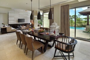 Un comedor moderno con una mesa grande, sillas y vistas a una piscina al aire libre.