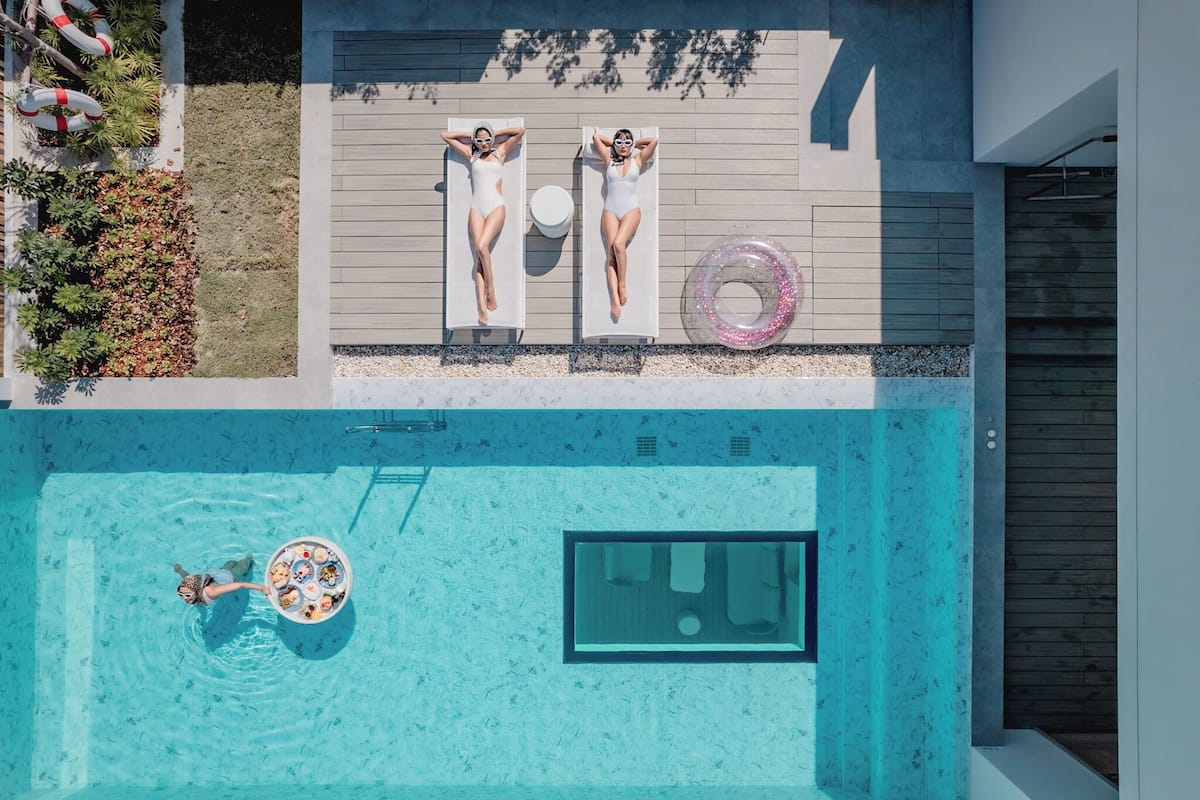 Vista aérea de un área de piscina moderna con dos tumbonas, un flotador y una mesa de billar.