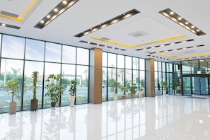 Un hall d’entrée spacieux, doté de grandes fenêtres, de plantes en pot et d’un éclairage moderne.