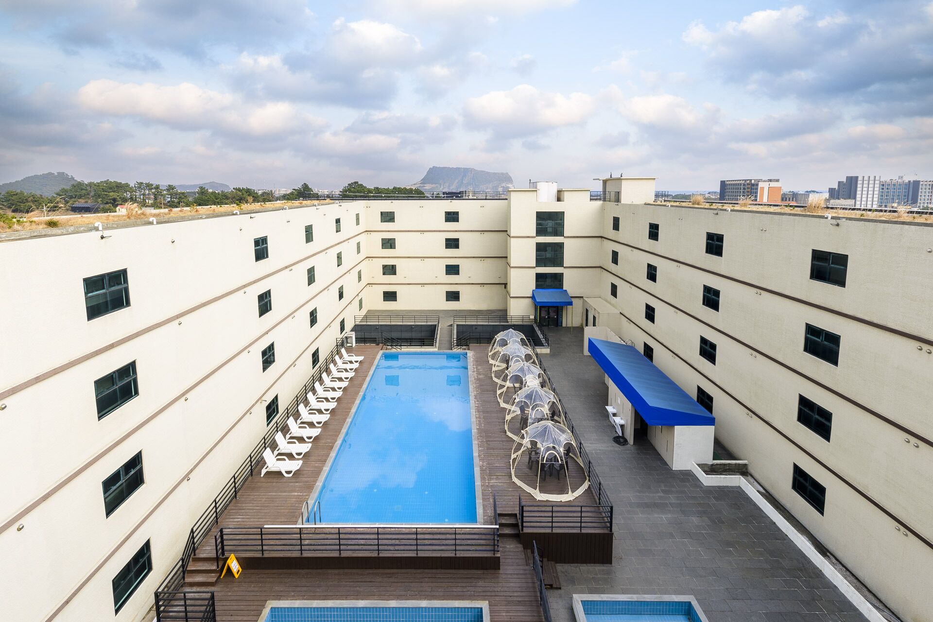 Un área de piscina en la azotea con varios niveles de balcones, una piscina central y mobiliario de exterior.