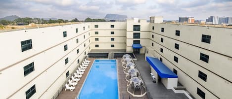 Un área de piscina en la azotea con varios niveles de balcones, una piscina central y mobiliario de exterior.