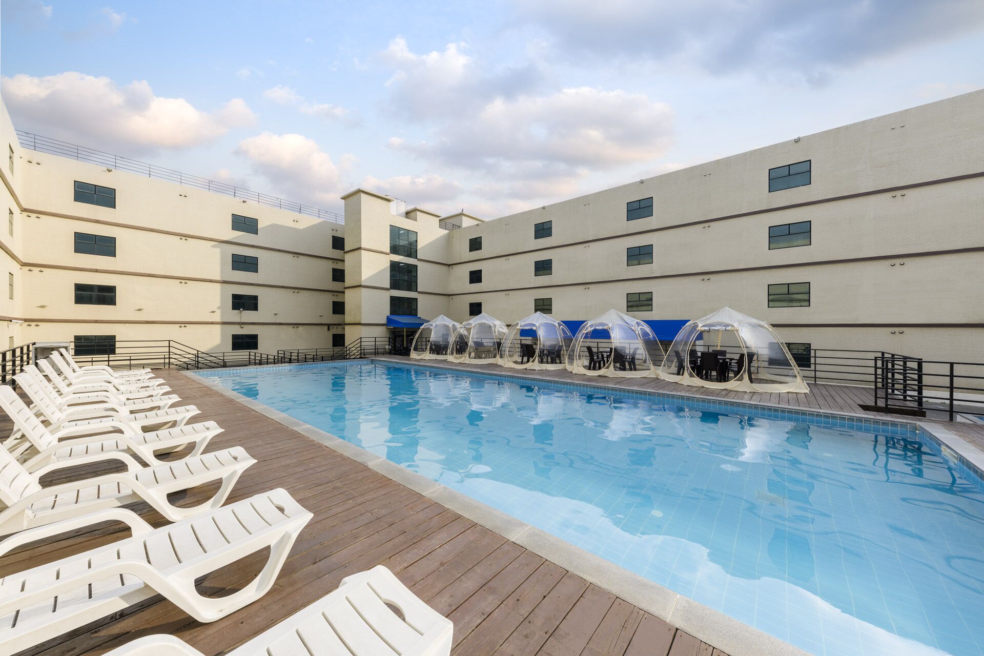A swimming pool with lounge chairs and covered seating areas.