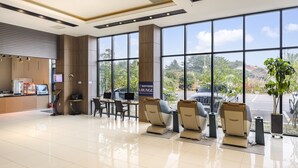 Een moderne lounge met grote ramen, een receptiebalie en massagestoelen.