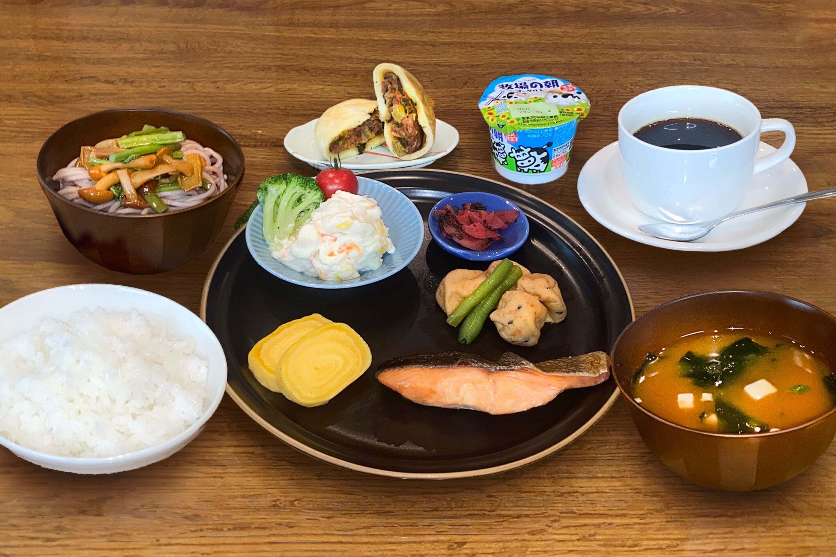 Diversitat de plats japonesos, com sushi, arròs i sopa, sobre una taula de fusta.