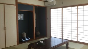 Perinteinen japanilainen huone, jossa on tatamimatto, puinen pöytä, liukuvat ovet ja suuri shoji-seinä.