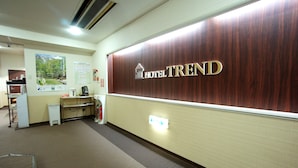 Zona de recepción con una pared de madera que muestra el nombre 'HOTEL TREND'.