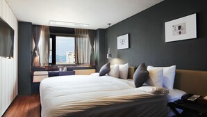 Une chambre d’hôtel avec un grand lit, une table de chevet avec une lampe, une fenêtre avec des rideaux et une vue sur la ville.