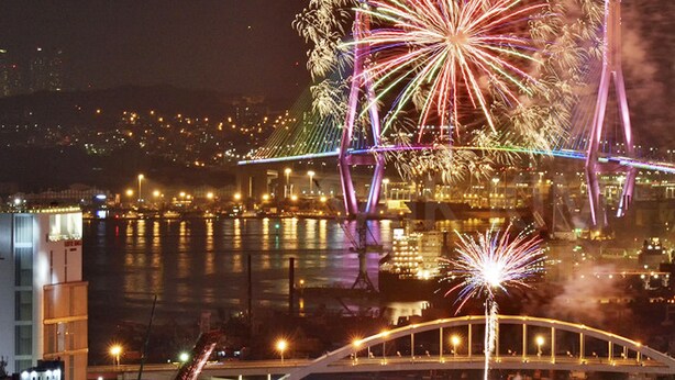 Une vue nocturne d’une ville, avec un pont et des feux d’artifice.