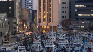 Un port de plaisance où sont amarrés de nombreux bateaux, un bâtiment imposant portant l’inscription « HOUND », et une enseigne « GRANCE HOTEL ».