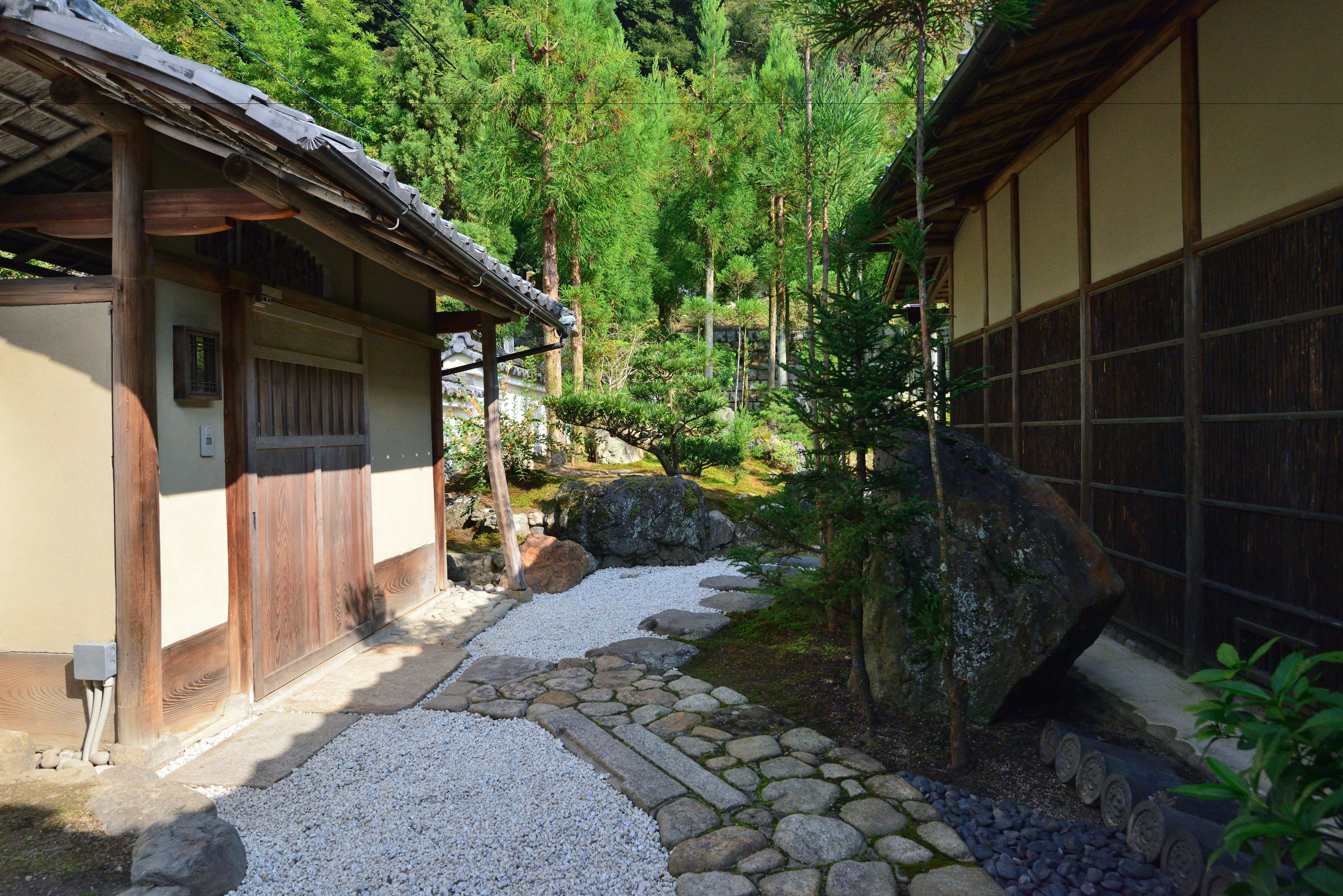 A traditional Japanese building with a stone pathway leading to a wooden gate.