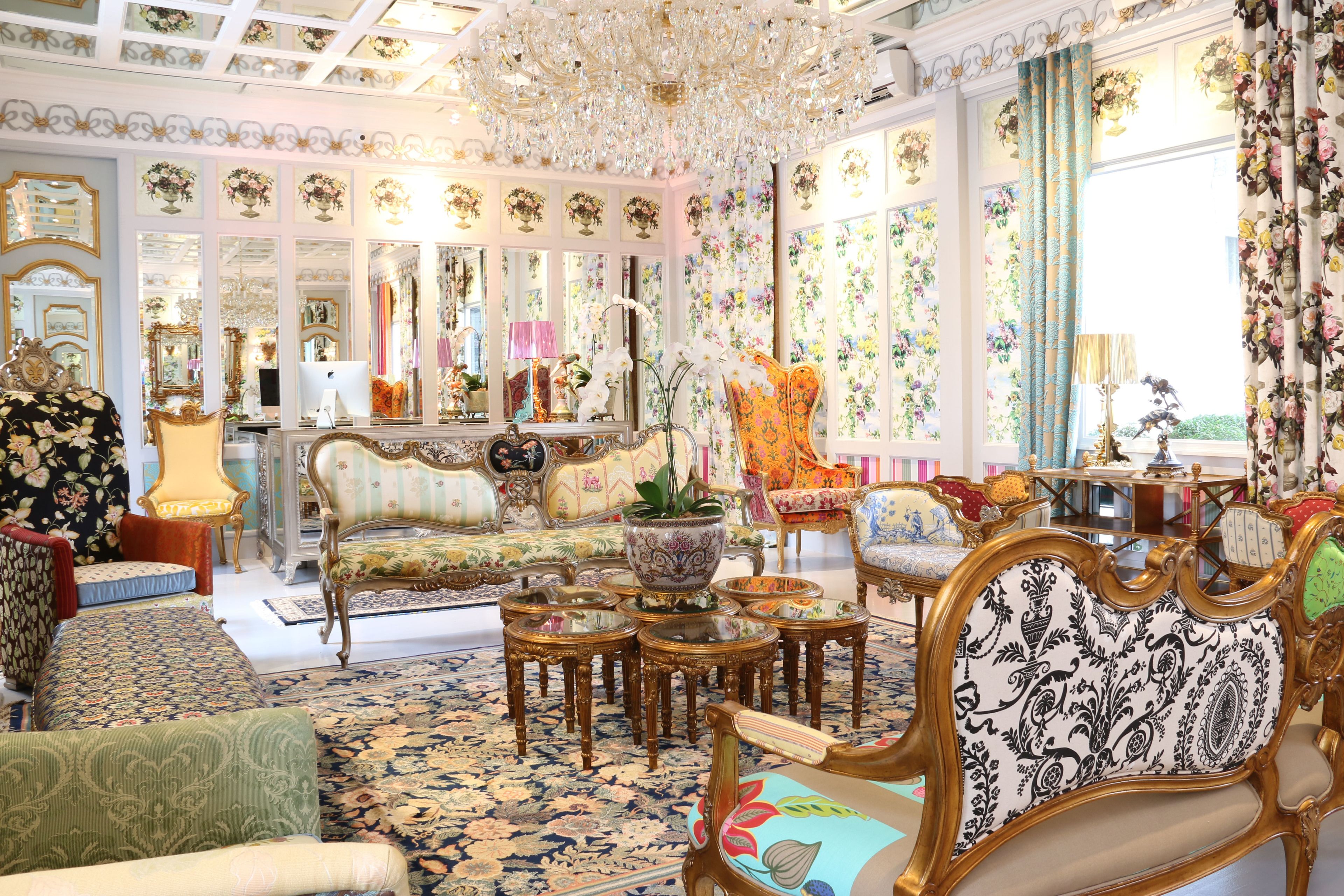 Una habitación lujosa con muebles ornamentados, una araña y un papel tapiz floral.