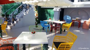 Un patio al aire libre con una mesa y sillas blancas, una escalera y un muro decorativo.