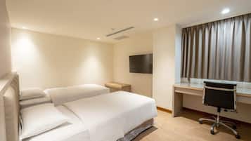 Een hotelkamer met een bed, een bureau, een stoel, een televisie en een raam met gordijnen.