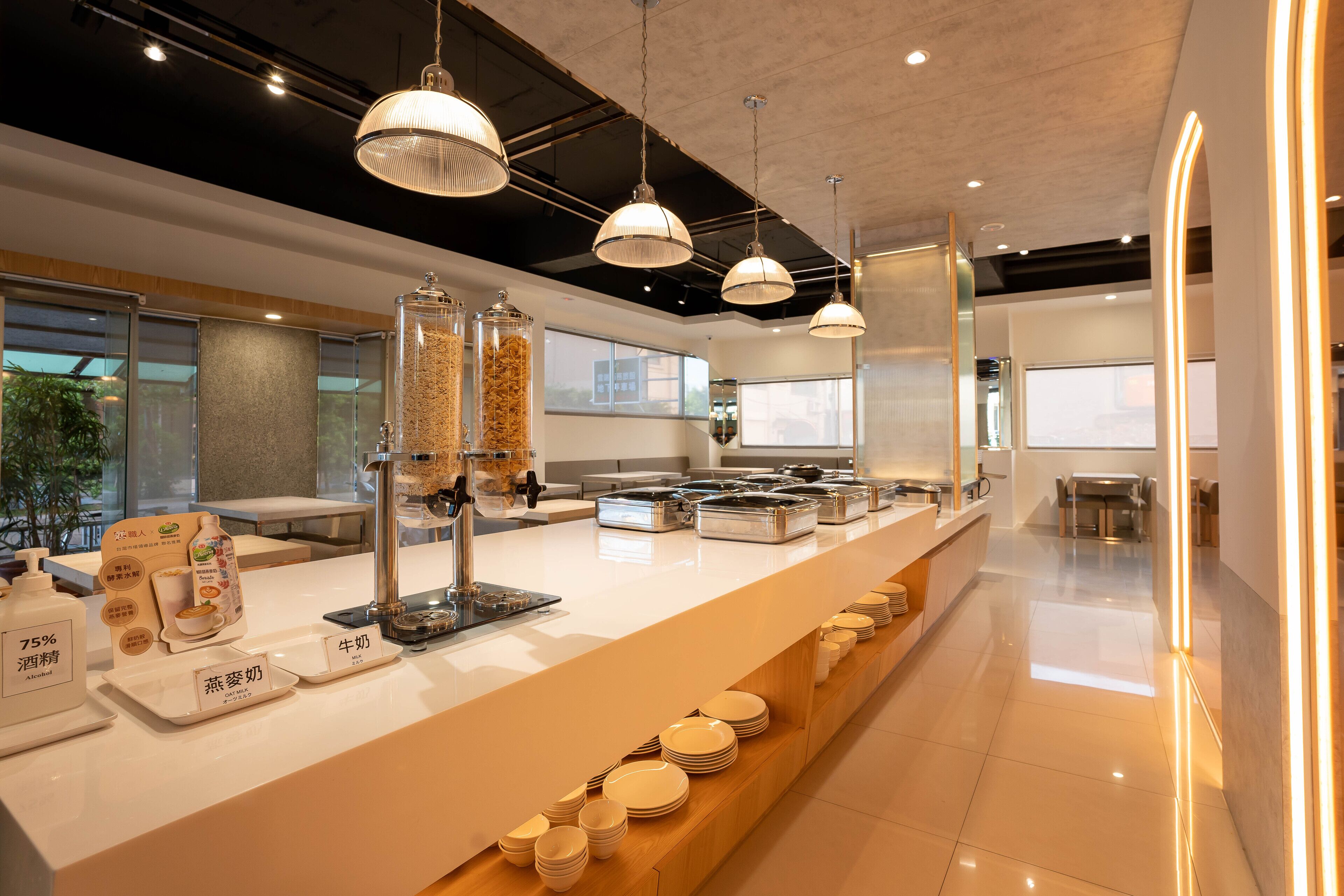 A modern buffet setup with a variety of food items and beverages, including a section for dairy products and a display of plates.