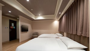 Habitación de hotel con una cama grande, un televisor montado en la pared, una silla y una puerta con un cartel.