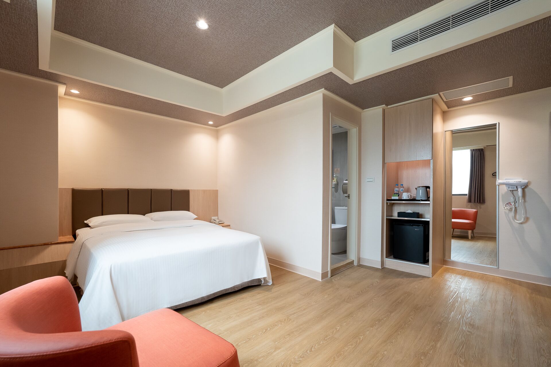Une chambre d’hôtel moderne équipée d’un grand lit, d’un bureau, d’une chaise, d’une salle de bain et d’une kitchenette.