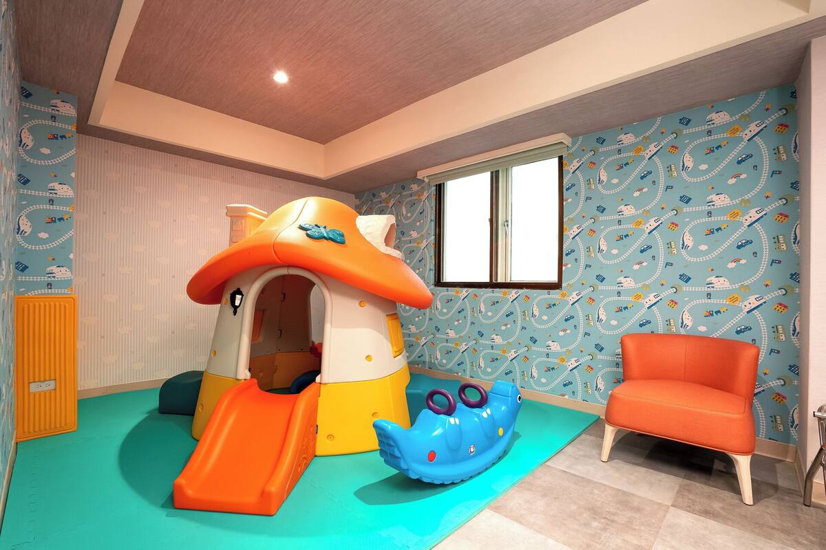 Un espace de jeux avec un toboggan, une cabane et un jeu sur le thème d’une baleine bleue.