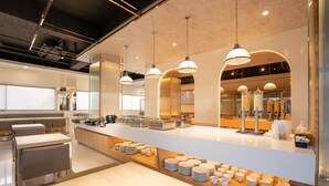 Un restaurante moderno con una barra central, varias zonas de estar e iluminación colgante.