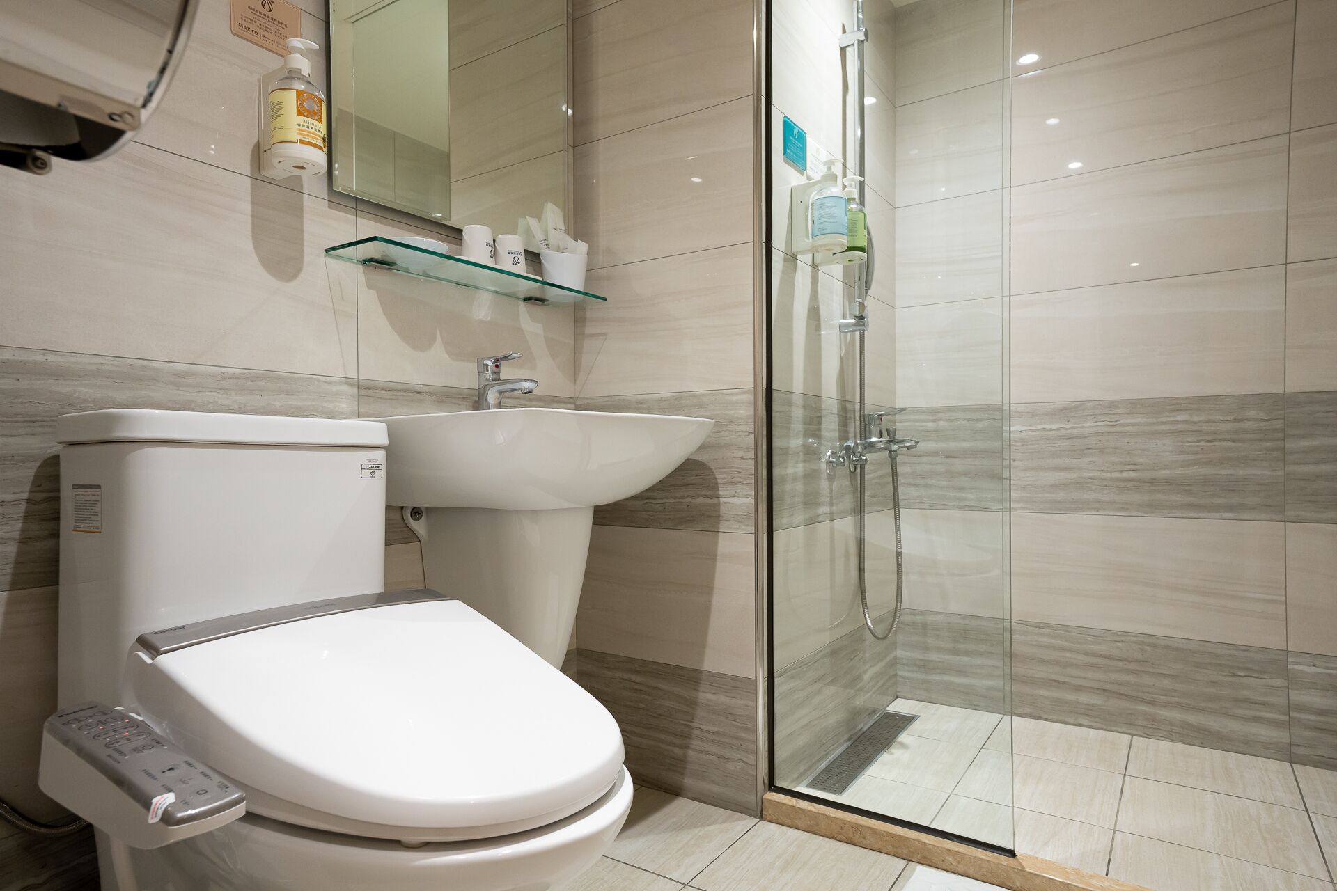 Un baño moderno con inodoro, lavamanos y cabina de ducha de vidrio.