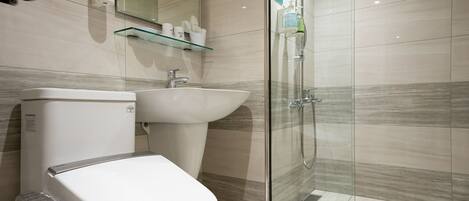 Un baño moderno con inodoro, lavamanos y cabina de ducha de vidrio.