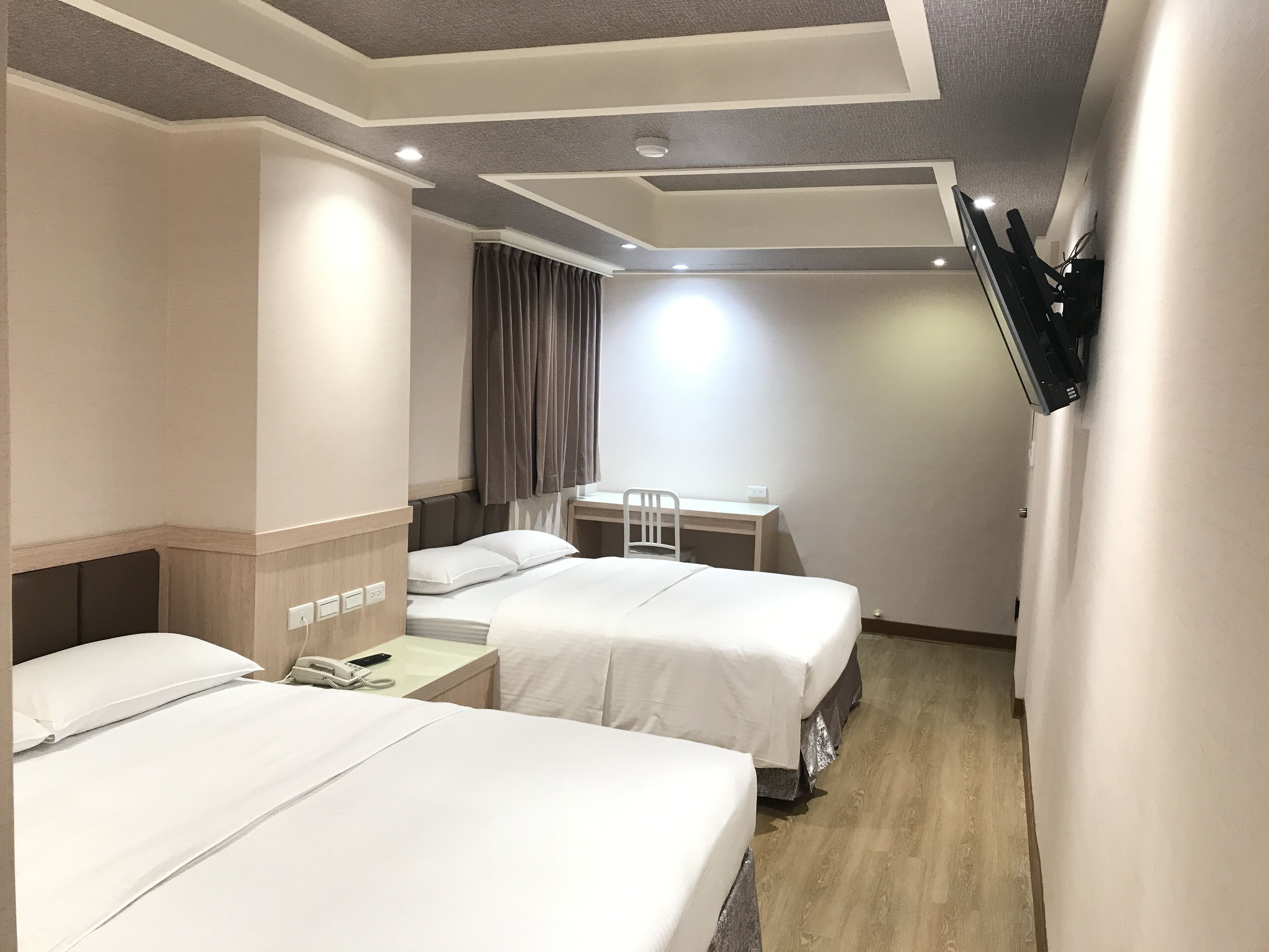 A hotel room with two beds, a desk, and a chair.