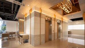 Un vestíbulo moderno con un diseño limpio y minimalista, que cuenta con un mostrador de recepción, zona de estar y ascensores.