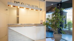 Un mostrador de recepción con un cartel que dice "The Cloud Hotel" y una planta en maceta grande a su lado.