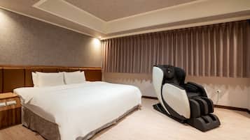 Ein Hotelzimmer mit einem Bett, einem Massagesessel und einem Nachttisch aus Holz.