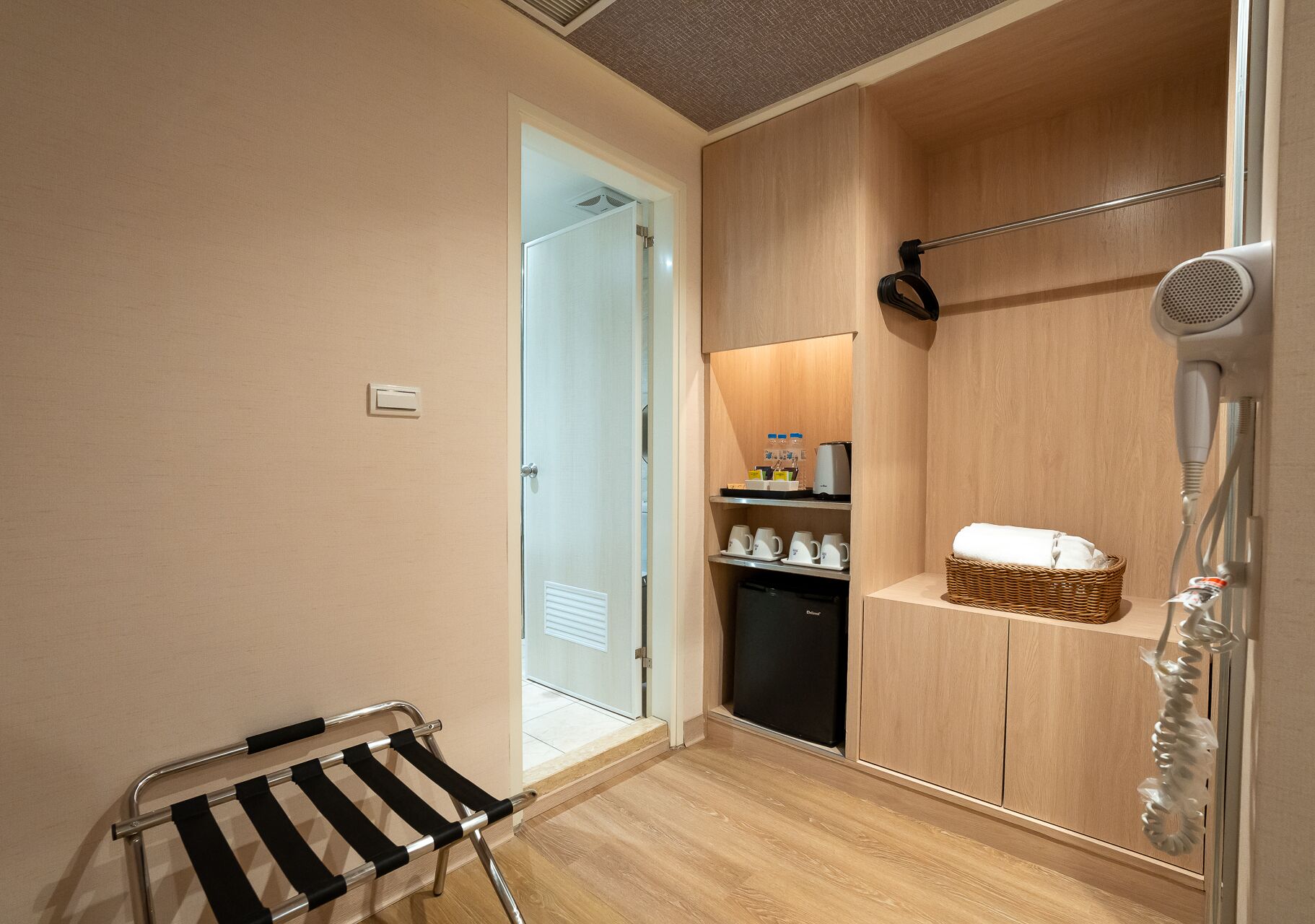 A hotel bathroom with a shower, a hairdryer, a towel, and a small shelf with toiletries.