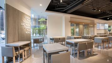 Un café moderne doté de nombreuses tables et chaises, de grandes fenêtres et d’inscriptions inspirantes sur les murs.