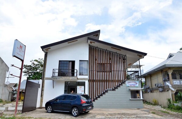A two-story building with a modern design, featuring a staircase leading to the upper floor and a sign indicating a laundry service. - Highway to H Inn - Danao (Danao)