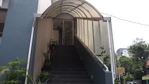 A staircase leading to a door with a metal gate, surrounded by potted plants. - Kemang Inn (Jakarta)
