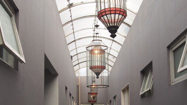A corridor with a glass ceiling, hanging lanterns, and potted plants. - Kemang Inn (Jakarta)