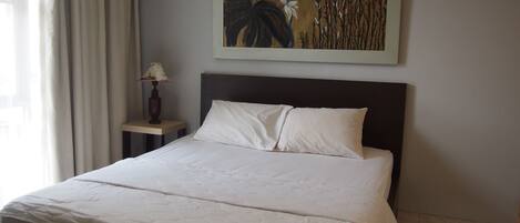 Una cama bien tendida con sábanas blancas en una habitación de hotel.