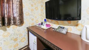 Une chambre d’hôtel équipée d’un bureau, d’une télévision, d’un téléphone et d’une bouilloire.