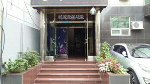 L’entrée d’un immeuble, avec une enseigne indiquant « 삼무빌 » et « 아시아스쿨 ».