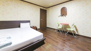 Une chambre d’hôtel avec un lit, une petite table et des chaises, une porte et un porte-manteau fixé au mur.