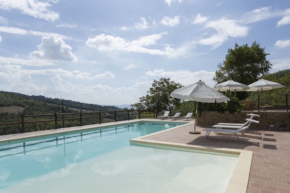 Una piscina al aire libre, sombrillas, tumbonas