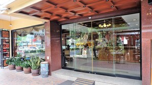 Un ristorante con facciata in vetro, piante in vaso all'esterno e soffitto in legno.