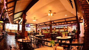 Un ristorante interno con soffitti alti, pareti in mattoni a vista e diversi tipi di sedute, tra cui tavoli e sedie.