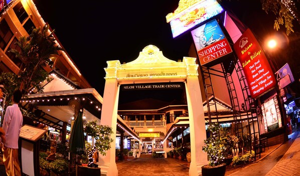 A shopping arcade with a sign for 'Silom Village Trade Center' and 'Thai classical drama' performance. - Silom Village Inn (Bangkok)
