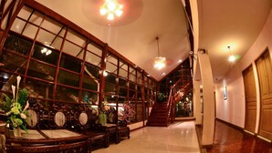 Un'ampia sala con soffitto alto, grandi finestre e una scala che conduce ai piani superiori.