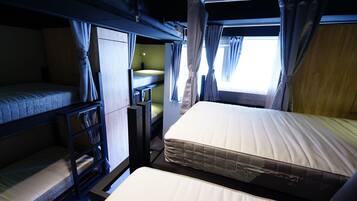 A bunk bed room with a window, curtains, and a bedside table.