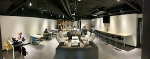 A modern lounge area with seating arrangements, tables, and a bar counter.
