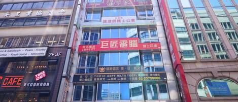 Un edificio de varios pisos que alberga diferentes comercios, como una cafetería, un hotel y un salón de karaoke.