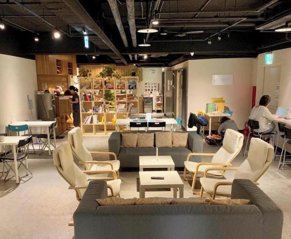 A modern interior with a sofa, chairs, tables, a bookshelf, and a counter area.